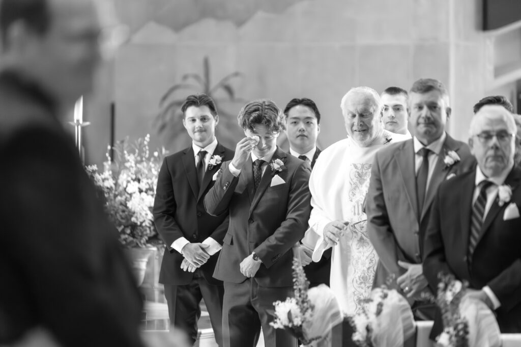 Groom wiping his eye from crying as he was watching his beautiful bride walk down the aisle towards him