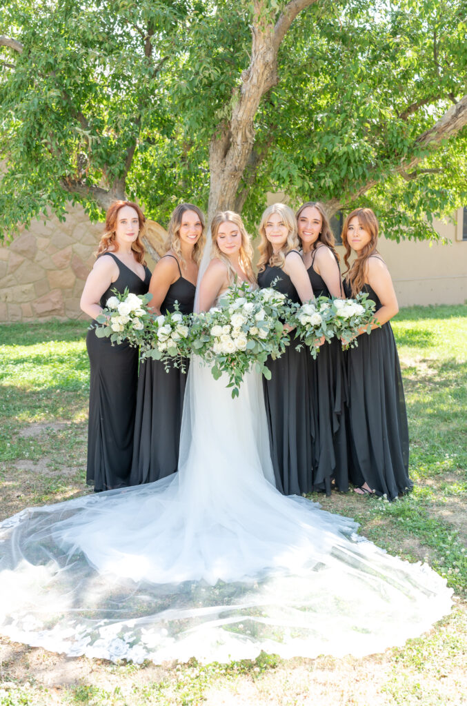 photo of the bride standing with all her bridesmaids holding their bouquets on wedding day 