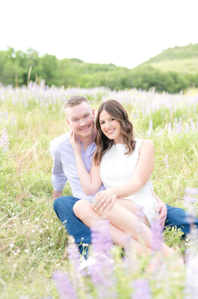 Couple sitting down together in grassy field with purple wildflowers at Colorado's Roxborough State Park