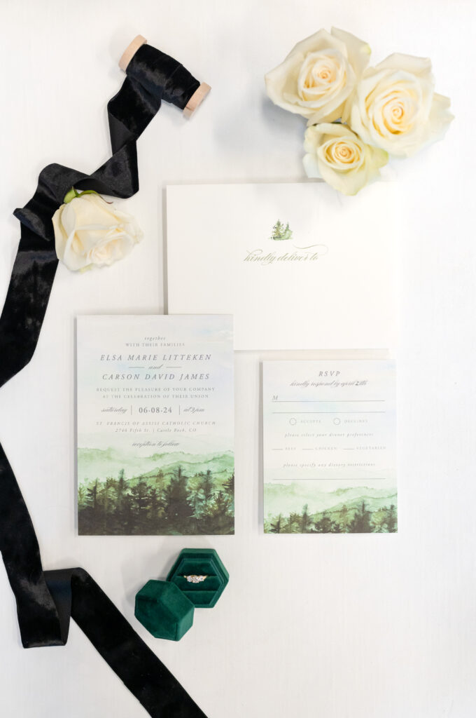 wedding detail photo of wedding invitation suite and black ribbon with white florals