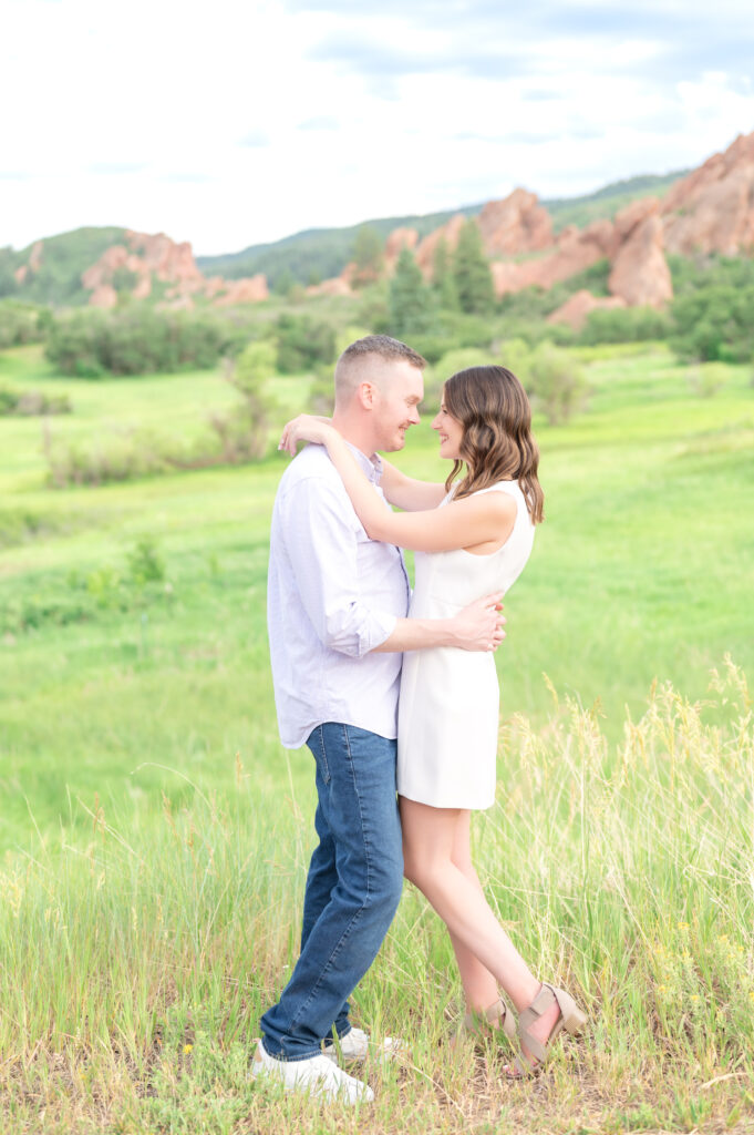 Couple slow dancing in a grassy field while smiling and looking at each other at Roxborough State Park in Colorado