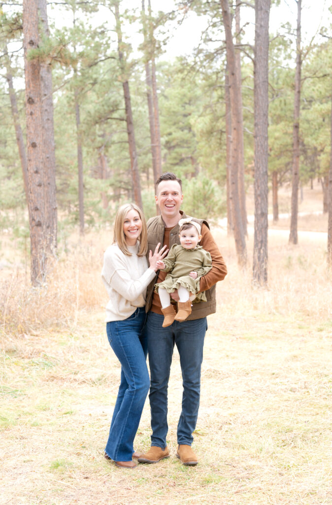 Young couple with their baby daughter stand in the Colorado woods to illustrate style guide for classic and timeless family photos