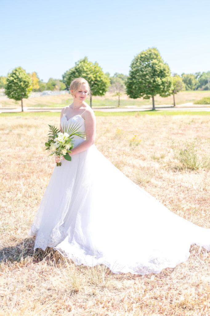 Bridal portrait of bride holding her greenery bouquet while looking down over her shoulder