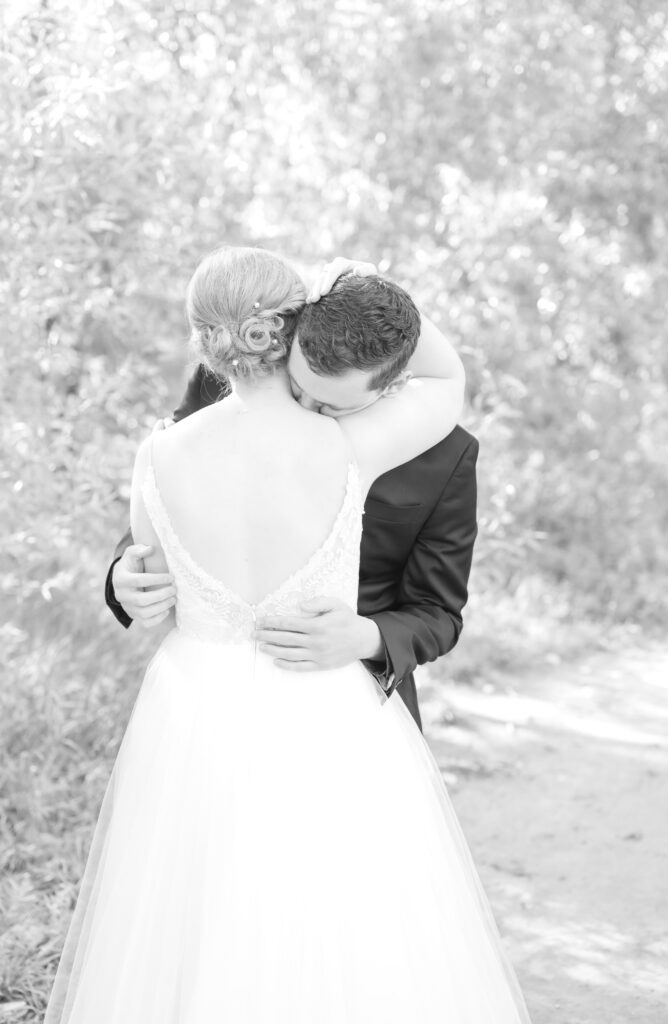 Bride and groom embrace on a sunlit path during their First Look in Colorado Springs