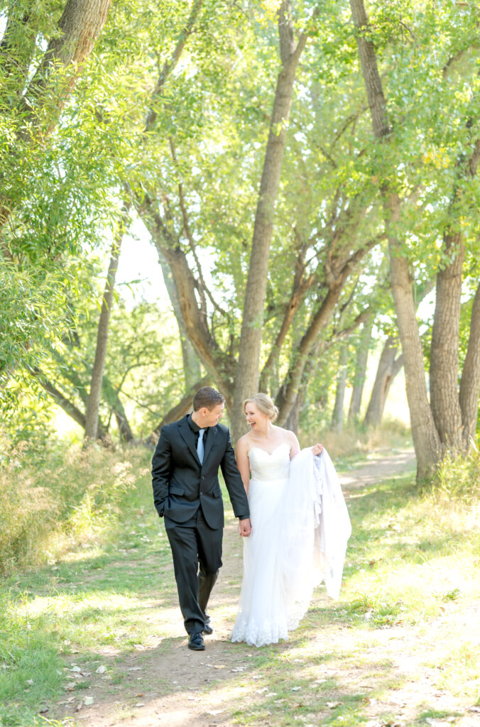 Bride and groom laughing and walking on path together holding hands on their intimate Colorado Springs wedding day