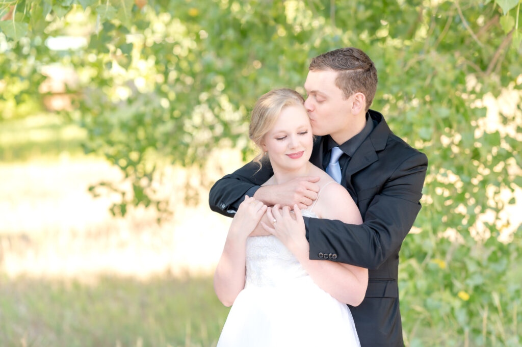 Young man embraces his bride from behind during their intimate Colorado Springs wedding day