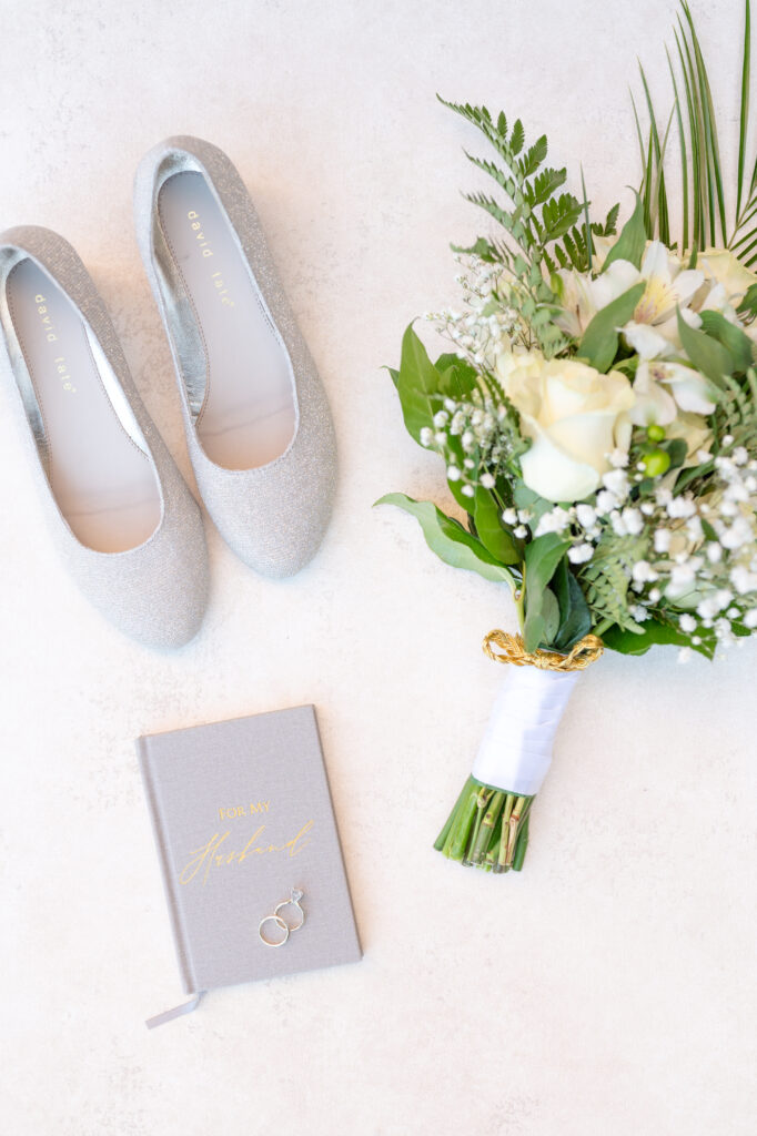 wedding photo of the bride's wedding day shoes, her bouquet, vow book, and wedding rings 