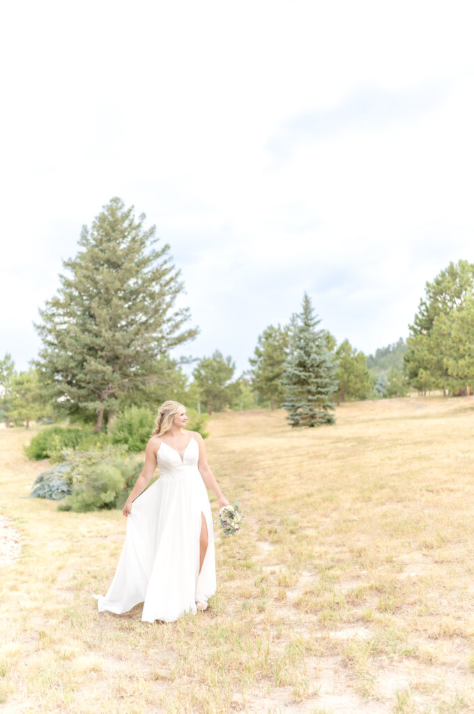 Bride walking through a field of trees in Colorado on her wedding day