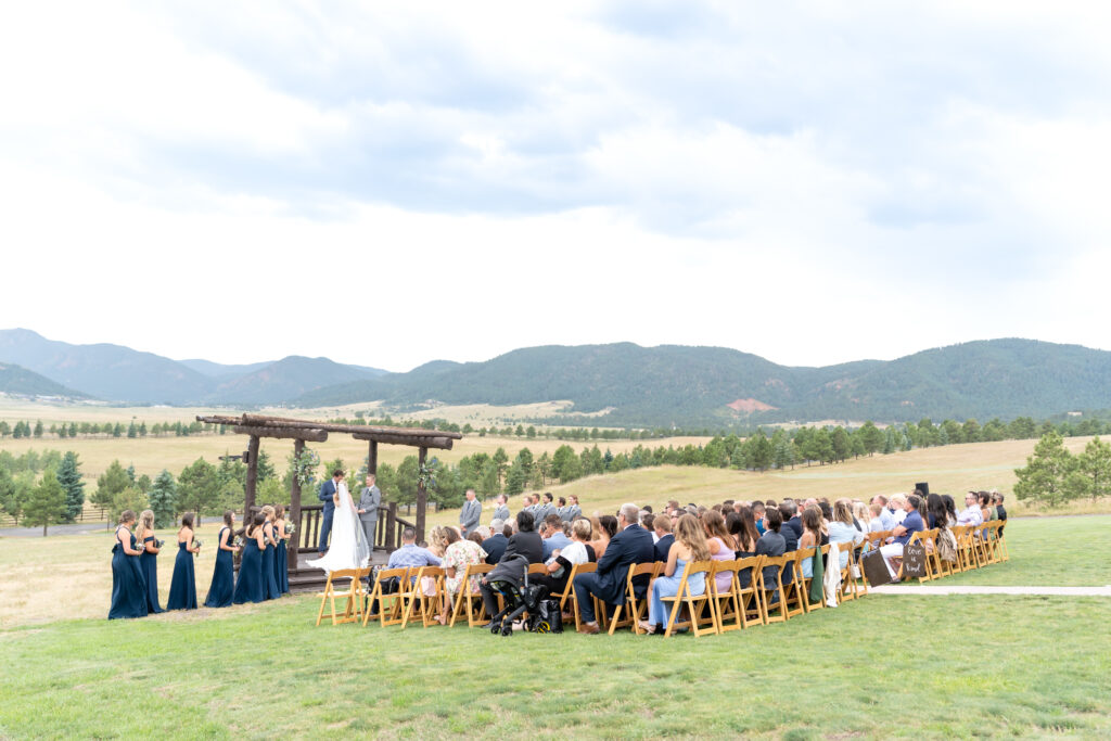 Guests seated on folding chairs against a mountain backdrop during a beautiful Colorado wedding