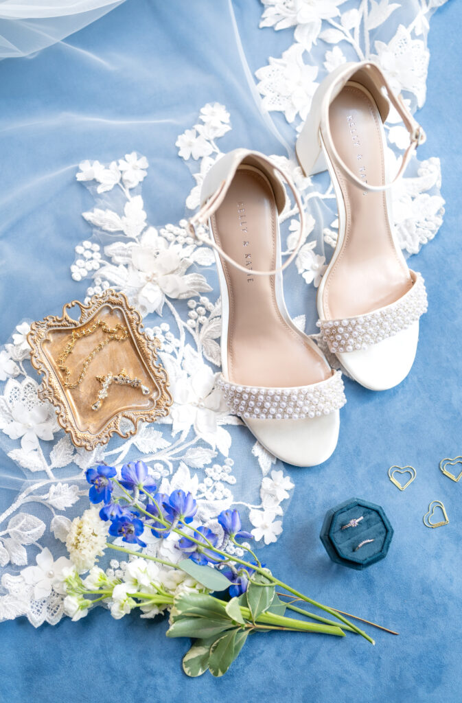 Detail of bride's shoes and jewelry arranged at the edge of her wedding veil