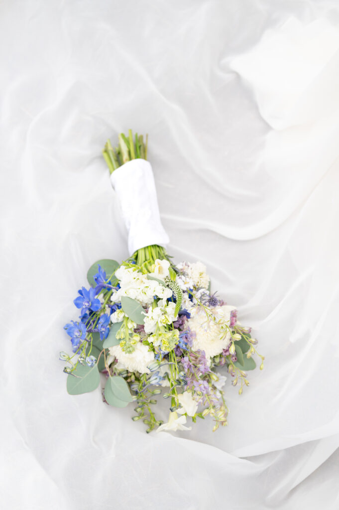 Detail of bride's bouquet with blue, white, and purple flowers