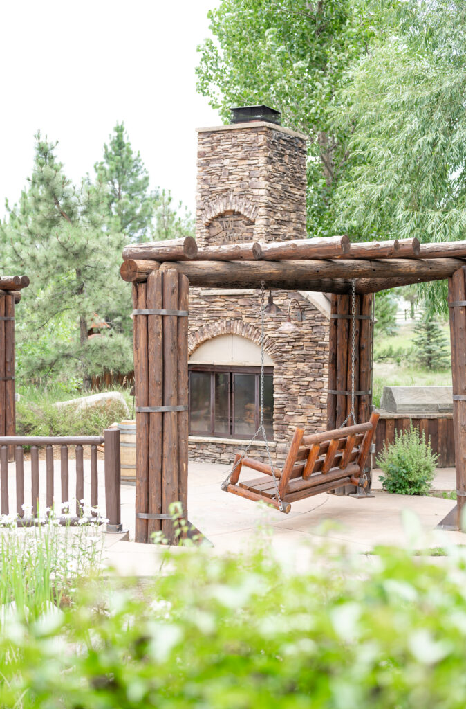 Outdoor brick fireplace next to a rustic wooden swing bench