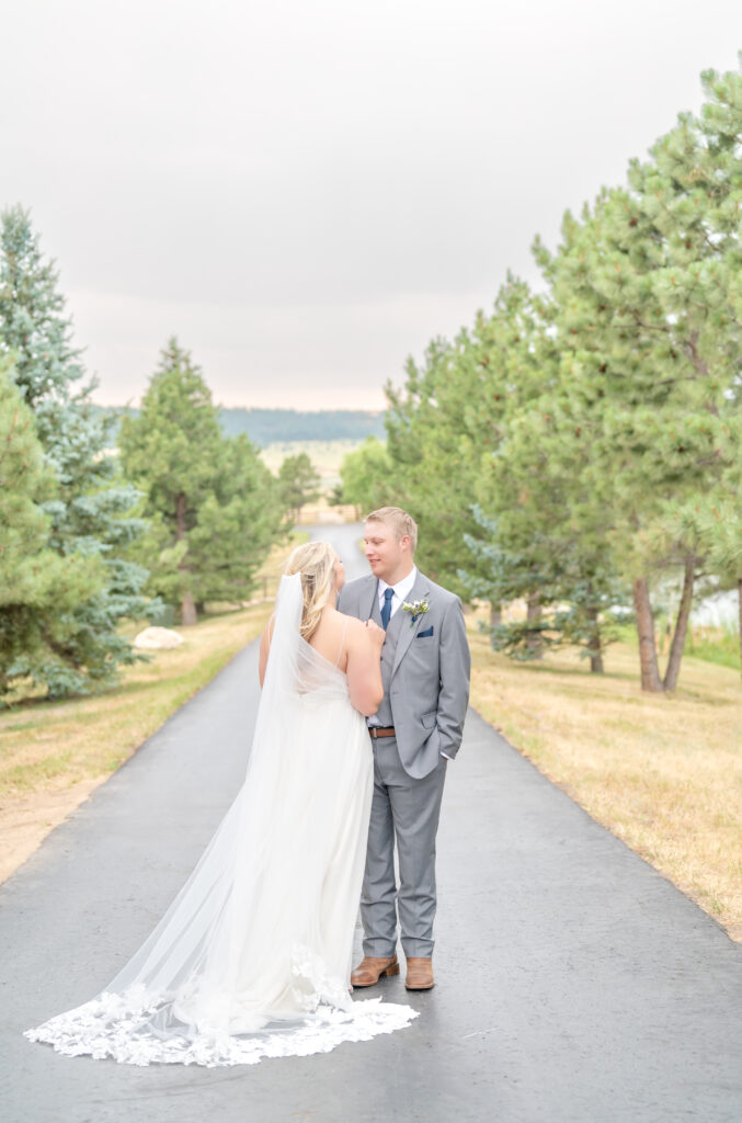 Bride and groom gaze into each other's eyes as they stand on a tree-lined path at their wedding venue in Colorado