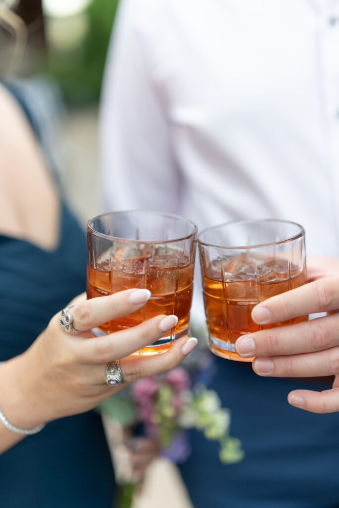 Couple clinking their glasses together as they celebrate a friend's wedding