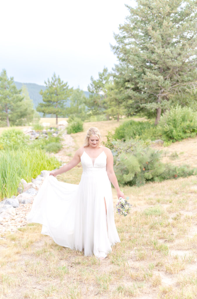 Bride standing near a stony creek bed surrounded by trees