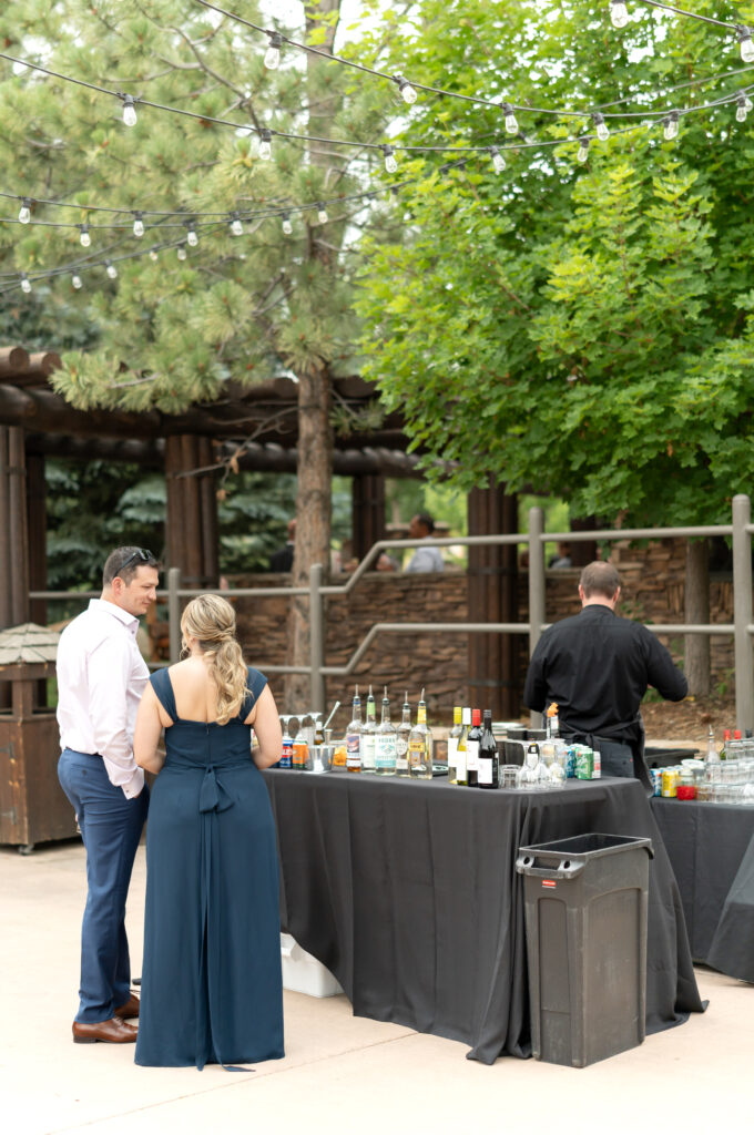 Couple stands near the drinks table at an outdoor wedding venue