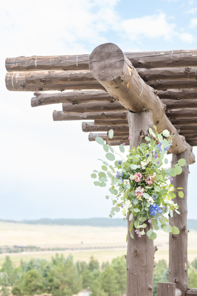 Spray of flowers attached to a rustic wooden arbor in preparation for the wedding ceremony