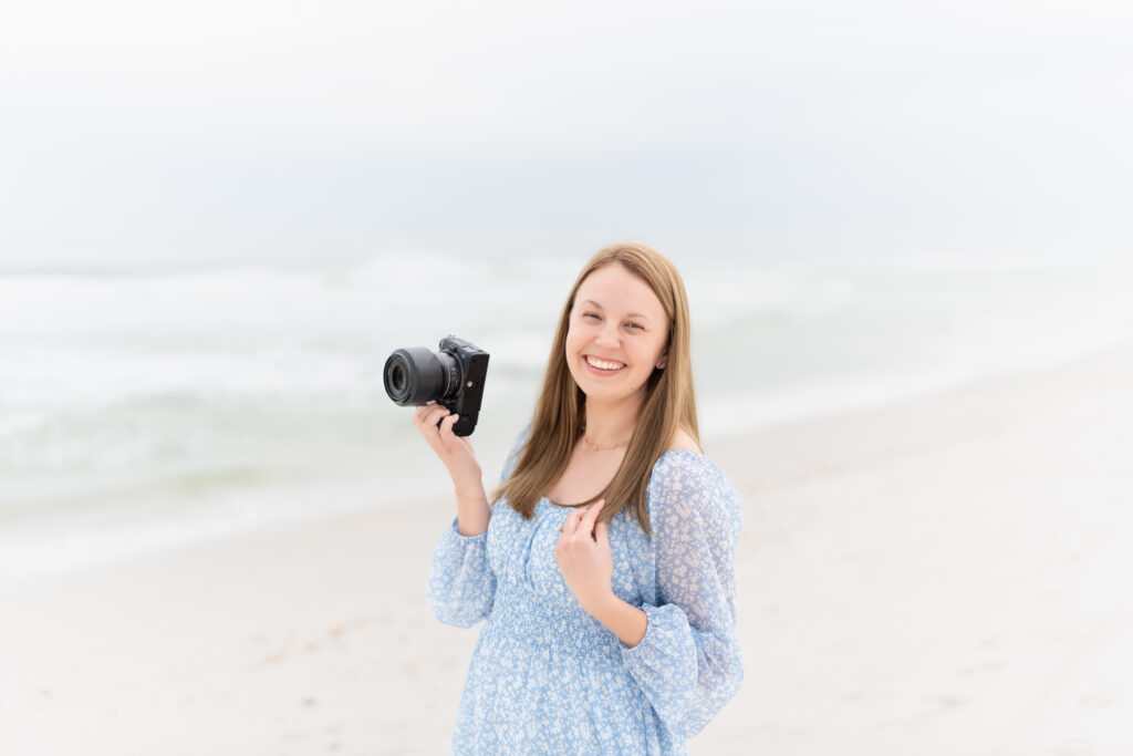 Colorado wedding photographer standing on a beach and holding her camera