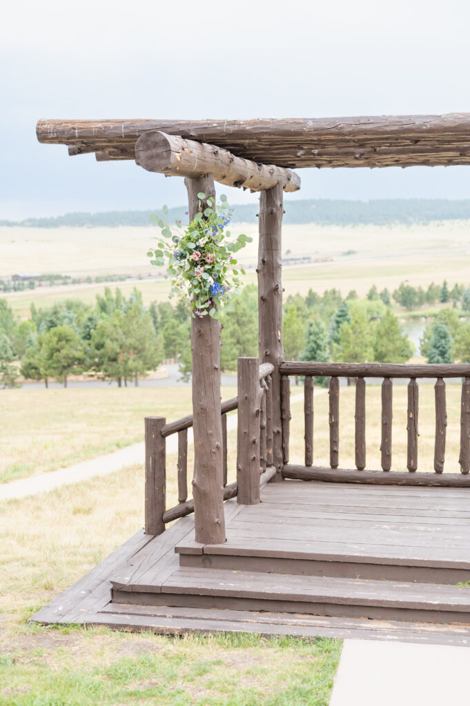 Rustic log wedding arbor overlooking fields and trees at a ranch wedding venue in Colorado