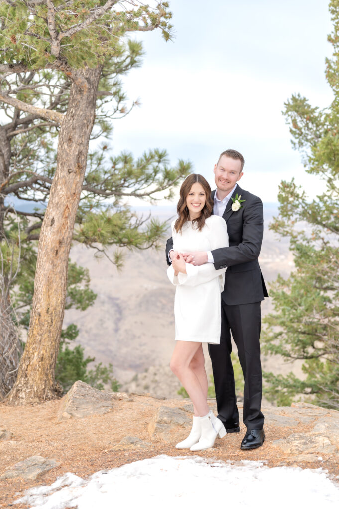 Bride and groom hug and and hold hands during their couples portraits at Lookout Mountain Colorado