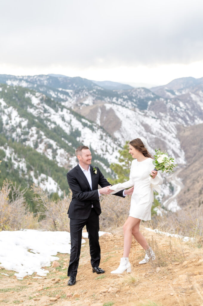 Groom holding his bride's hand as she walks down the hill during their couples portraits in the mountains 