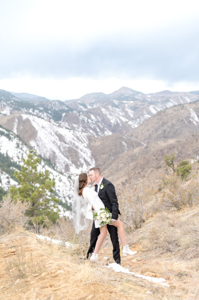 Groom dips his bride back as they share a kiss together with the mountain backdrop after their elopement ceremony 