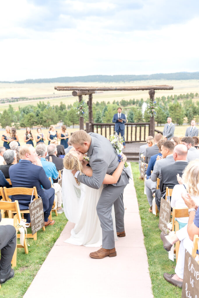 Groom dips the bride for a kiss in the aisle during their outdoor Colorado wedding at Spruce Mountain Ranch