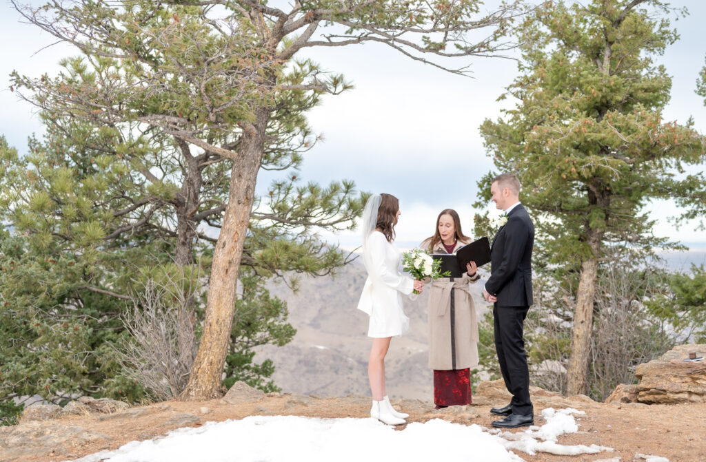 Bride and groom sharing their private outdoor elopement ceremony with their officiant at Lookout Mountain Colorado