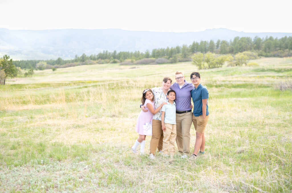 Family standing in a meadow with foothills in the background during their Colorado Springs family photos session