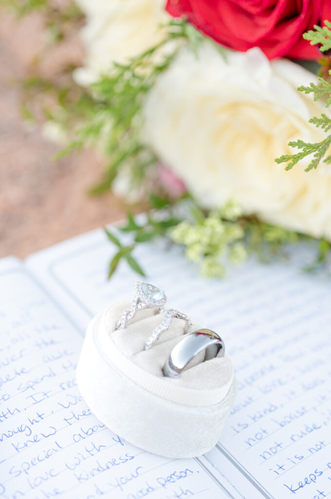 Wedding day rings on a journal page with a bouquet of red and white roses in the background