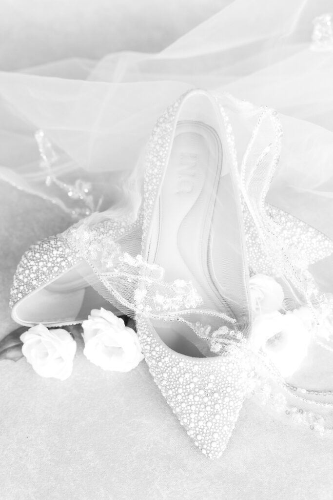 black and white wedding detail photo of bride's shoes laying underneath the veil 