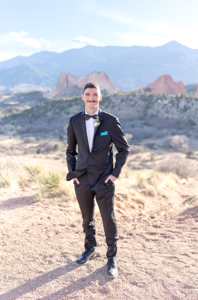 Groom standing with his hands in his pant pockets while smiling towards the camera for photo