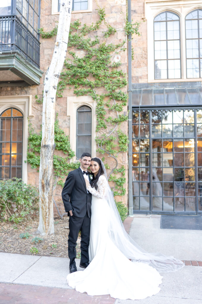 Bride laying her hand on her groom's chest as they smile for a portrait at Glen Eyrie Castle on their elopement day