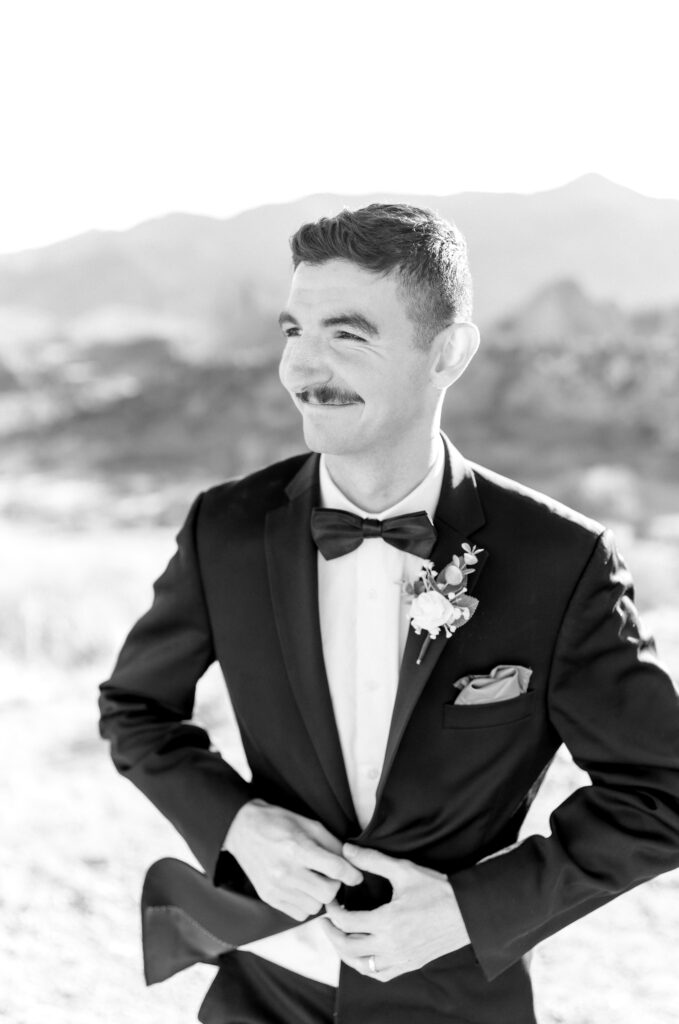 Portrait of groom smiling on his Colorado Springs elopement day while butting upon his suit jacket