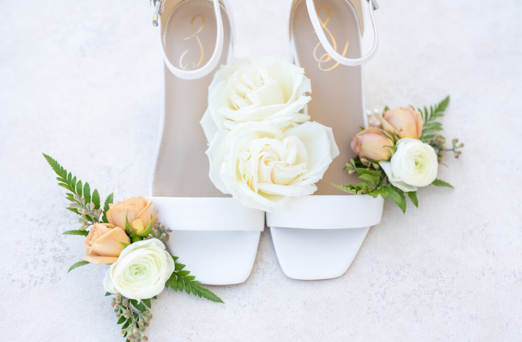 Wedding detail photos of bride's white shoes with roses nestled around them
