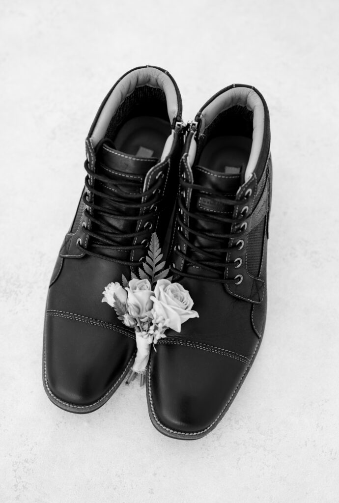 Wedding detail photo of the groom's boutonniere laying in between his shoes