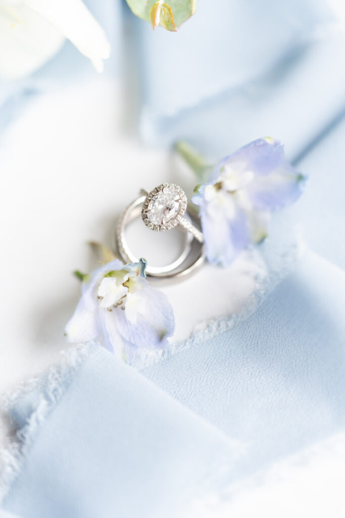 Detail of wedding ring framed between blue flowers