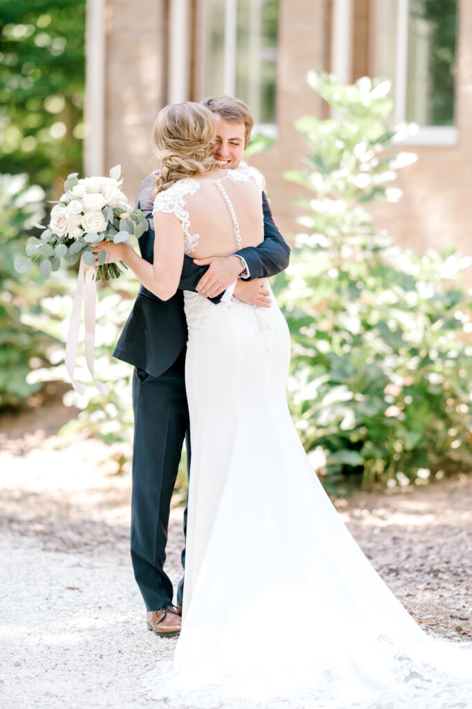 Colorado wedding photographer in bridal gown embraces her groom during their wedding first look