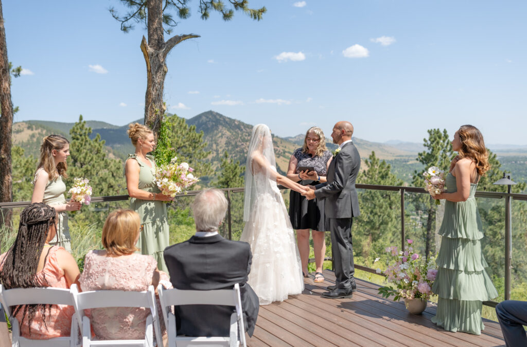 Bride and groom hold hands during their outdoor wedding ceremony at Flagstaff House Boulder Colorado
