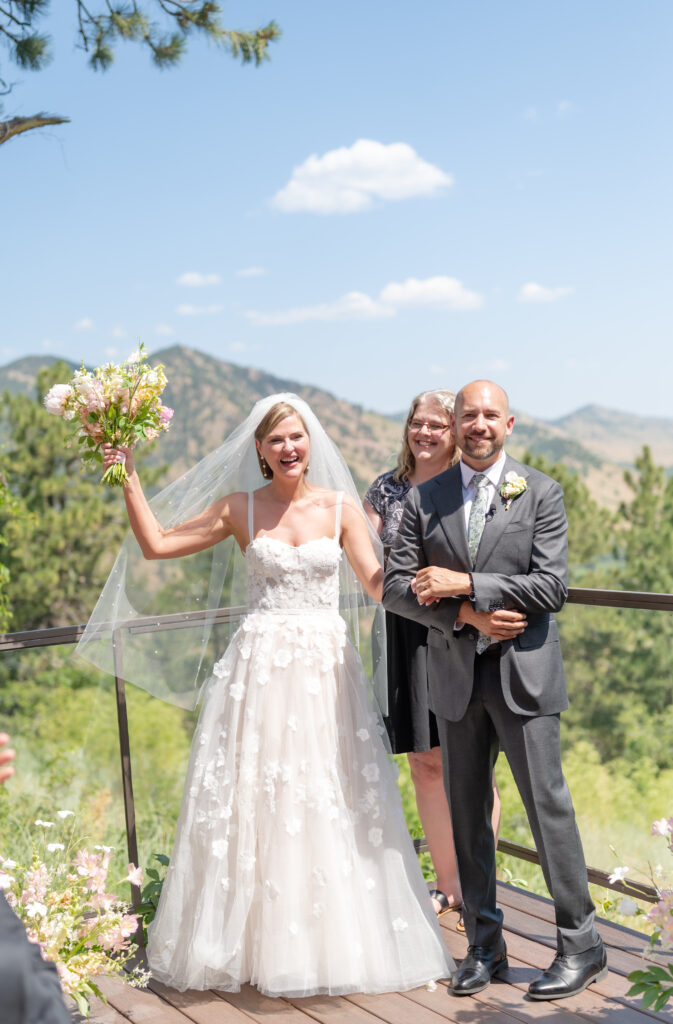 Bride and groom smiling as they stand together after their wedding ceremony on a balcony overlooking the Colorado mountains