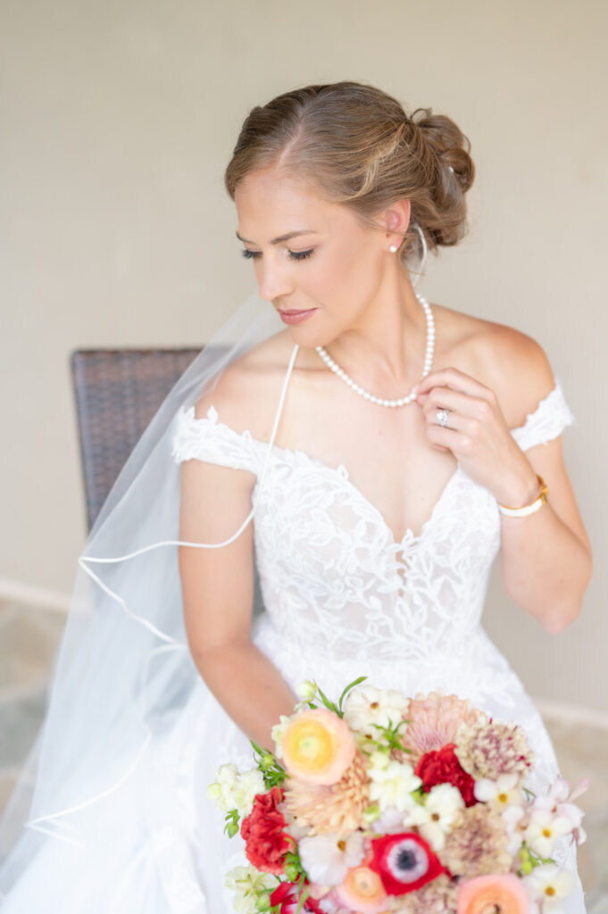 Bride in her wedding dress, holding a bright bouquet of summer flowers, as she gets ready for her First Look