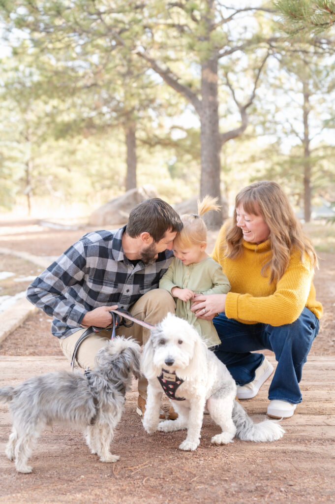 Parents laughing with their daughter and pets during an outdoor family photoshoot in Colorado Springs