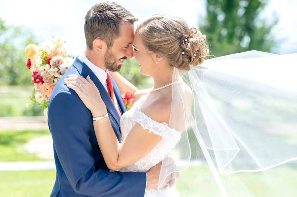 Bride and groom touch foreheads, smiling, as they stand together in the sun at the Flying Horse Resort in Colorado Springs