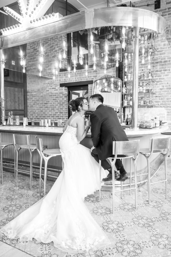 Bride and groom exchange a kiss as they share a drink together at the bar of the Mining Exchange Hotel in Colorado