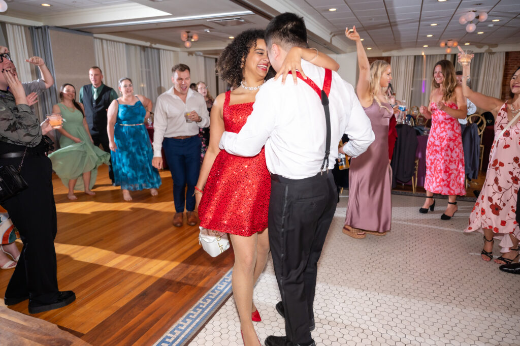 Newly married woman in red sequined dress smiling as she dances with her husband during their wedding reception in Colorado