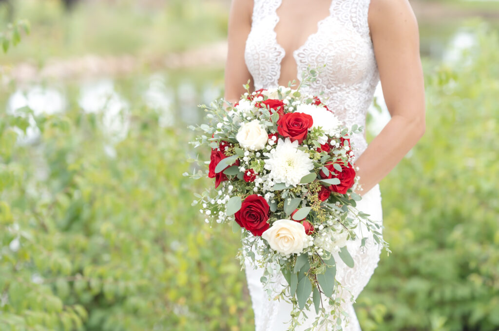 Close-up of the bride's floral bouquet with greenery, and red and white florals