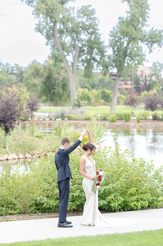 Groom twirling his bride around to see her dress during their first look at The Pinery at The Hill in Colorado 