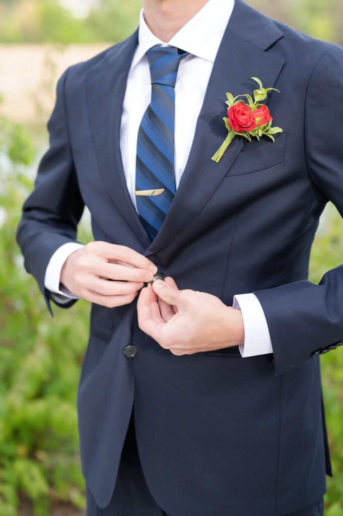 Detail photo of the groom buttoning up his suit jacket on his wedding day at The Pinery 