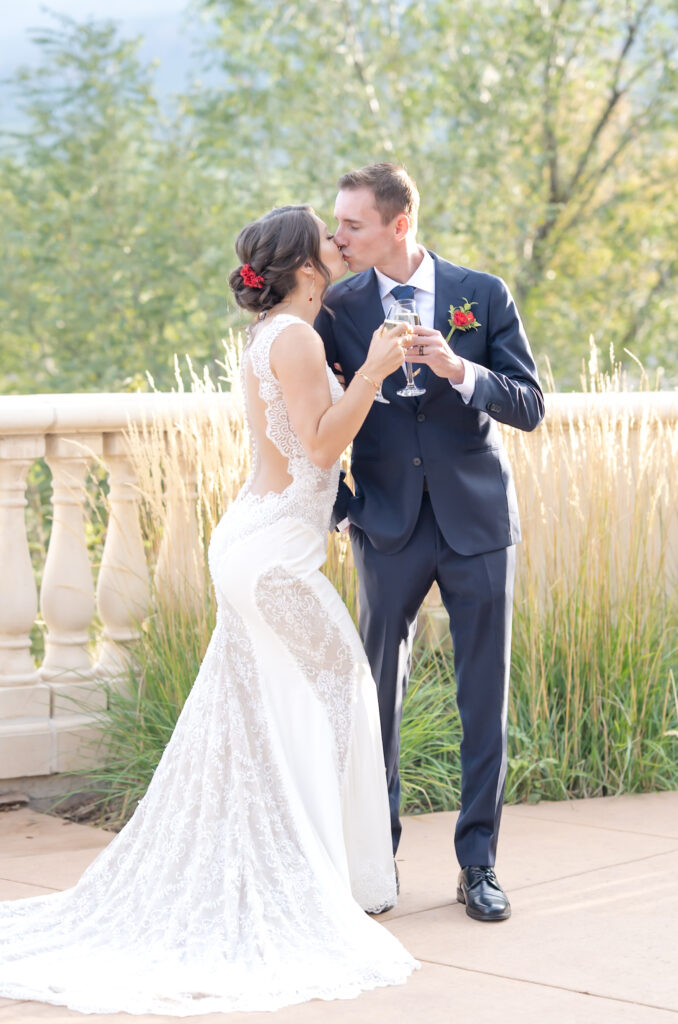 Bride and groom kissing and toasting their glasses of champagne at The Pinery