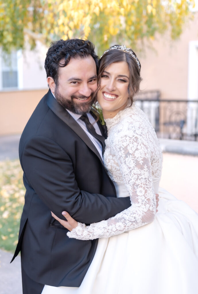 Bride and groom hugging and smiling towards camera together on their Colorado Springs wedding day 